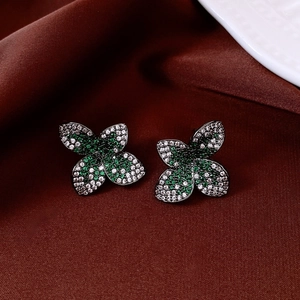 Close-up of vintage flower earrings with green and white zircons on red silk backdrop