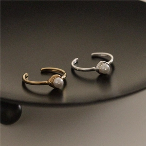 Detailed close-up of adjustable silver and gold pearl rings on a black matte tray