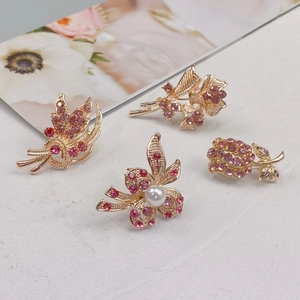 Detailed view of four golden rhinestone brooches with pink crystals and imitation pearls
