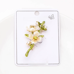 Detail of floral twig brooch with pearlescent petals, green enamel, and white pearls