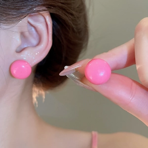 Macro shot of glossy pink round bean stud earring worn on earlobe for a sweet style