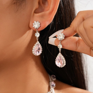Macro shot of silver drop earrings with pink pear-cut crystals and round zircon accents