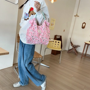 Close-up of pink floral quilted handbag with blue checkered handles in cafe setting