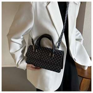 Close-up of black handbag featuring blue geometric pattern and gold-tone metal hardware