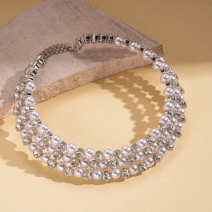 Three-layer faux pearl choker necklace with rhinestones on a stylish stone display