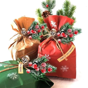 Three festive Christmas gift bags in red, brown, and green with pine needles and berries