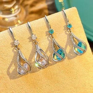 Close-up of sparkling teardrop zircon earrings on a beige display stand for weddings