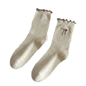 Beige crew socks with colorful speckles, brown wavy edges and bow embroidery detail