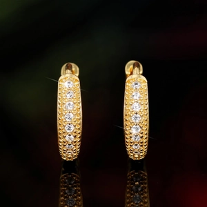 Macro detail of classic gold hoop earrings with sparkling cubic zirconia on dark surface