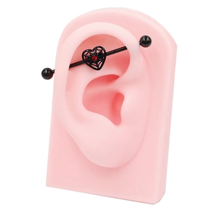 Industrial barbell piercing featuring a black heart spider web and red zircon stone