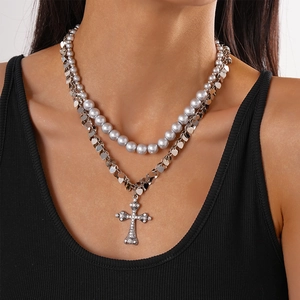 Detail of layered silver chain with heart sequins, pearls and rhinestone cross pendant