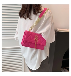 Detail of fuchsia quilted crossbody bag with gold S-logo tassel and chain strap