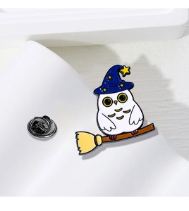 Detailed enamel pin featuring a white owl with a wizard hat riding a broomstick accessory