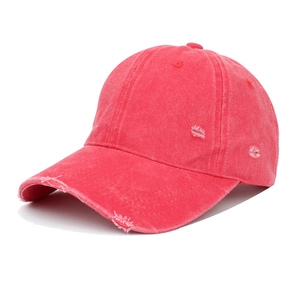 Close-up of vintage distressed red baseball cap with washed denim texture and frayed holes