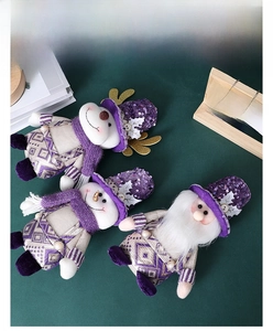 Detail of purple sequin Santa, snowman and deer plush dolls on a dark green background