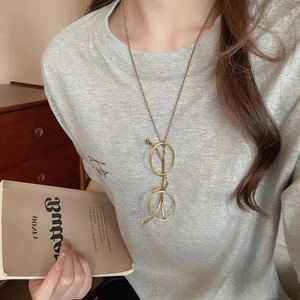 Detail of creative gold glasses pendant necklace worn in a vintage literary setting