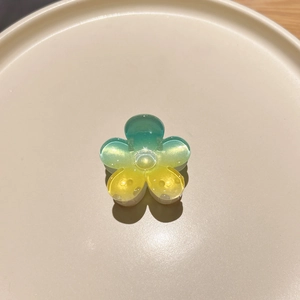 Detail of gradient yellow and green plumeria hair claw clip with glossy acrylic finish