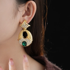 Macro side view of vintage golden fan earrings with green gemstones and rhinestones