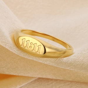Macro shot of gold oval signet ring featuring 11:11 engraved numbers on smooth satin