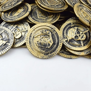 Dettaglio macro di monete pirata in oro antico con rilievo di teschio, spade e forziere