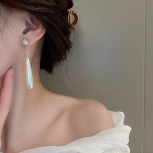 Close-up of elegant French vintage teardrop pearl earrings worn on a model's ear