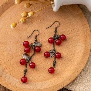 Detailed close-up of vintage red beaded tassel earrings on a decorative wooden tray