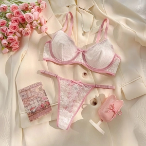 Detailed close-up of pink and white lace lingerie set featuring floral patterns and bows