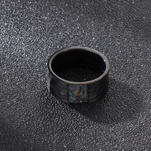 Vue détaillée d'une bague noire en acier avec texture martelée et incrustation d'abalone