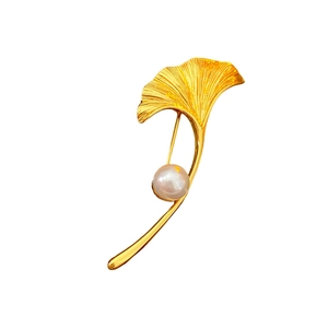 Elegant gold maple leaf brooch with textured finish and a white pearl center accent