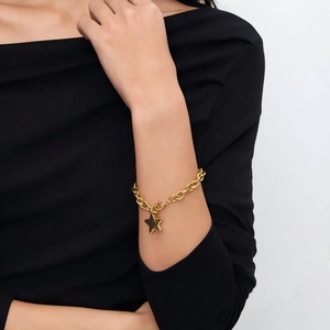 Bracciale con stella in acciaio inossidabile lucido su polso con finitura oro minimalista