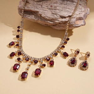 Elegant gold vintage jewelry set with red gemstones, necklace and earrings on stone