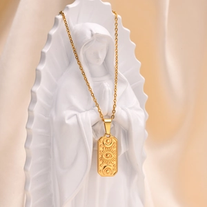 Detail view of a gold sun moon and eye relief pendant displayed on a classic plaster statue