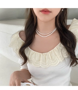 Gros plan d'un collier de perles blanches à double rang porté par un mannequin élégant