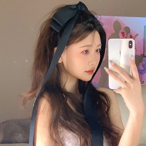 French style black oversized bow hair clip with long ribbons worn by a model in a bedroom