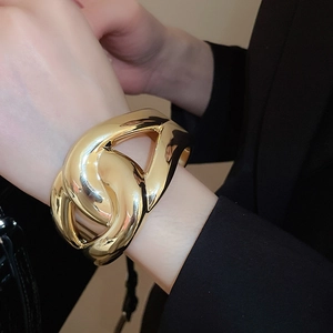 Detailed close-up of a wide chunky gold chain link bracelet in an organic abstract design