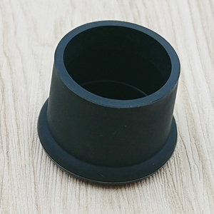 Top view of a durable black food-grade silicone bottle cap on light wooden surface