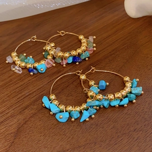 Bohemian gold hoop earrings with turquoise and natural stone beads on a wooden background