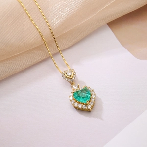 Close-up of gold necklace with emerald heart pendant and micro-pave diamond halo