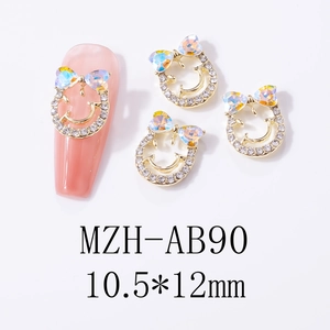 Detailed view of smiling face bowknot nail charms with aurora rhinestones and gold alloy