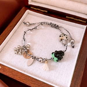 Detail of beaded tassel bracelet with glass heart and stone beads in a wooden jewelry box