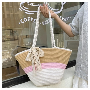 Détail d'un sac cabas tissé tricolore avec anses en corde et nœud décoratif en dentelle