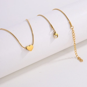 Detail of golden heart pendant necklace with sleek snake chain on white display