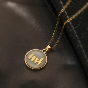 Macro detail of gold family pendant featuring silhouettes on a grey mother of pearl base