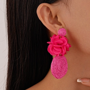 Detail showing the layered pink fabric flower and woven raffia design on the earring