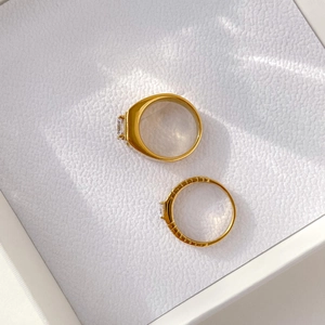 Close-up of gold couple rings with one gear design band and one inlaid diamond in a gift box