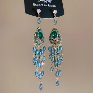 Macro shot of bohemian green teardrop earrings with colorful beadwork and long tassels
