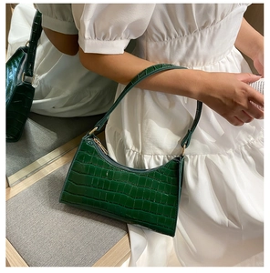 Detail of dark green crocodile texture underarm bag with gold zipper shown in mirror view