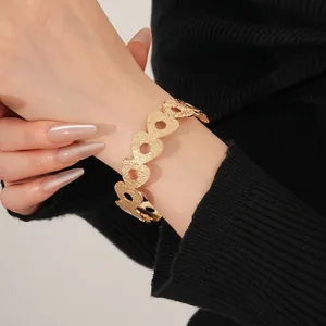 Minimalist gold hollow heart cuff bracelet with hammered texture on female wrist