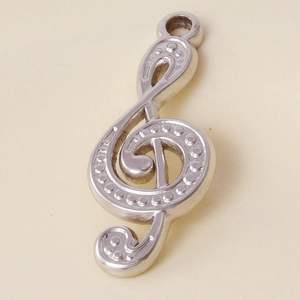 Close-up of a silver treble clef pendant made of stainless steel with dotted texture