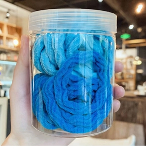Close-up of blue gradient seamless hair ties in a clear jar with high elasticity texture